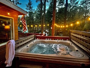 Una vasca idromassaggio circondata da un pontile in legno, con una bandiera americana e luci decorative sullo sfondo.