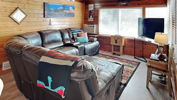 A cozy living room with a large sectional sofa, a television, and a fireplace.