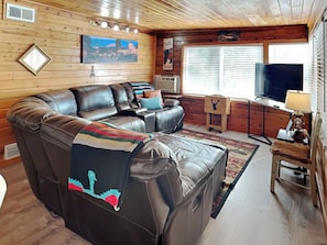 A cozy living room with a large sectional sofa, a television, and a fireplace. - The Elk Meadow Cozy Cabin by Ruidoso Vacation Rentals (Ruidoso)