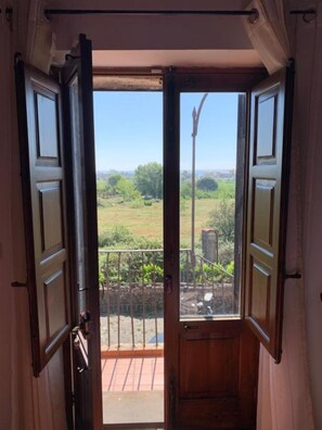 Puerta de madera con vista a un patio cercado y cielo despejado.