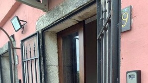 Entrada de un edificio con puerta de madera y reja de metal negro.