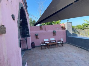 Ein Patio mit einer rosafarbenen Wand, einem schwarzen Tor und einem Tisch mit Stühlen.