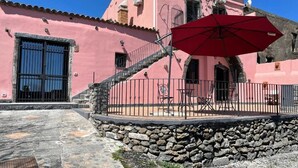 Un edificio rosa con un muro de piedra y un paraguas rojo.