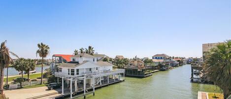 Un canal con un muelle, casas y palmeras.