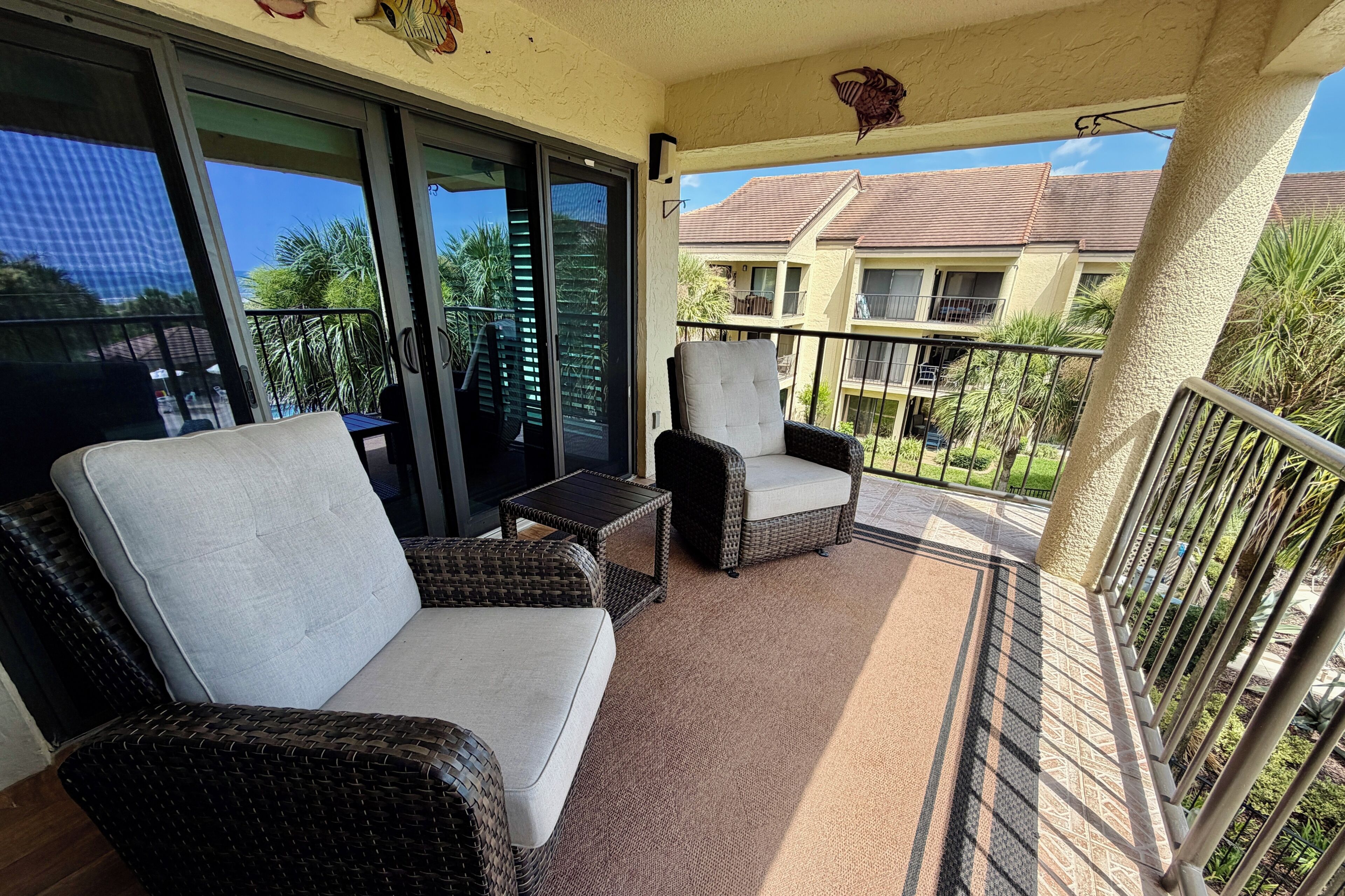 A balcony with wicker furniture, a small table, and a view of a residential building.