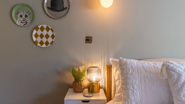 Ein Schlafzimmer mit einem Bett, einem Nachttisch mit Lampe, einer Wanduhr und dekorativen Tellern.