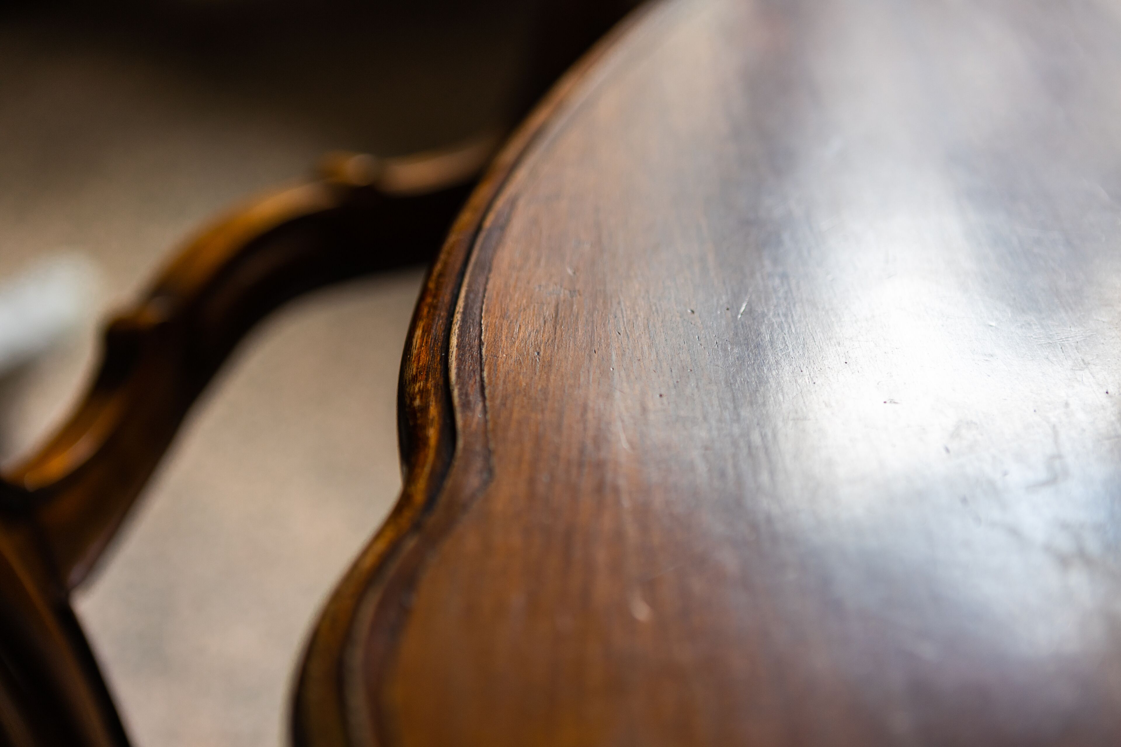 A close-up of a wooden surface with a glossy finish and a carved edge.