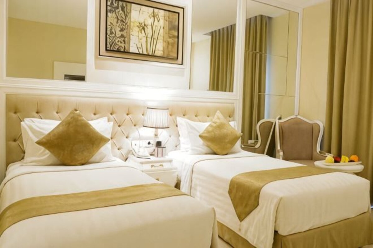 Habitación de hotel con dos camas, una mesita de noche, una silla, un espejo y un frutero.