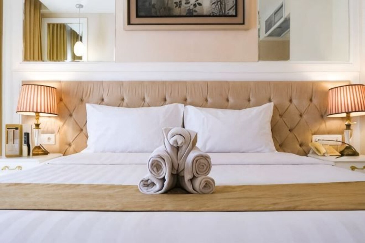 Habitación de hotel con una cama grande, dos lámparas de noche y un cuadro en la pared.