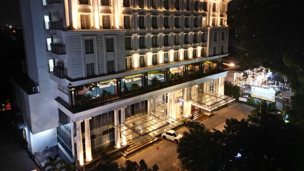 Ein mehrstöckiges Hotel im modernen Stil, mit Balkonen auf jeder Etage und einer Glasfassade im Erdgeschoss.