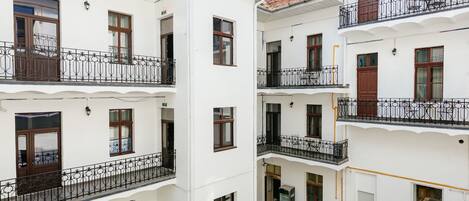 Un patio con varios pisos de edificios blancos, mobiliario exterior y un césped verde.