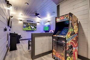 Een speelkamer met een groot scherm, een spelconsole en een lessenaar.