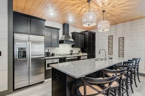 Enjoy cooking in this kitchen with a large island, bar stools, stainless steel appliances, and a granite countertop.