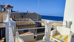 Un balcón con muebles de mimbre, una lámpara y vista al mar.