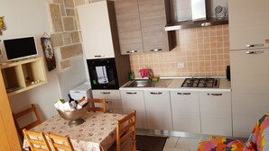 Una cocina compacta con comedor, que incluye estufa, lavamanos y un refrigerador pequeño.
