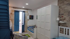 Un dormitorio con cama, armario, una mesita y una silla.