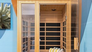 Sauna, jossa on puuseinät ja lasiovi, sekä penkki ja pyyhkeet.