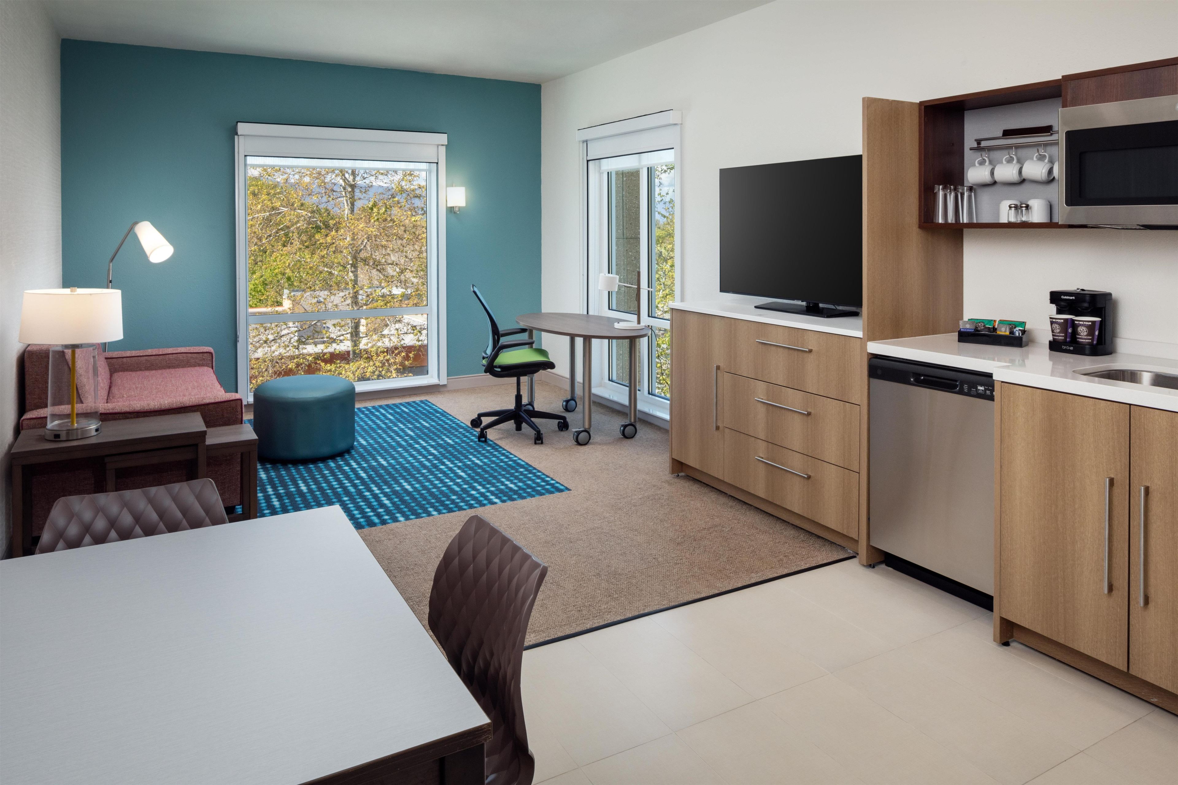 Una cocina moderna con una televisión de pantalla plana, una cafetera y un comedor con mesa y sillas.
