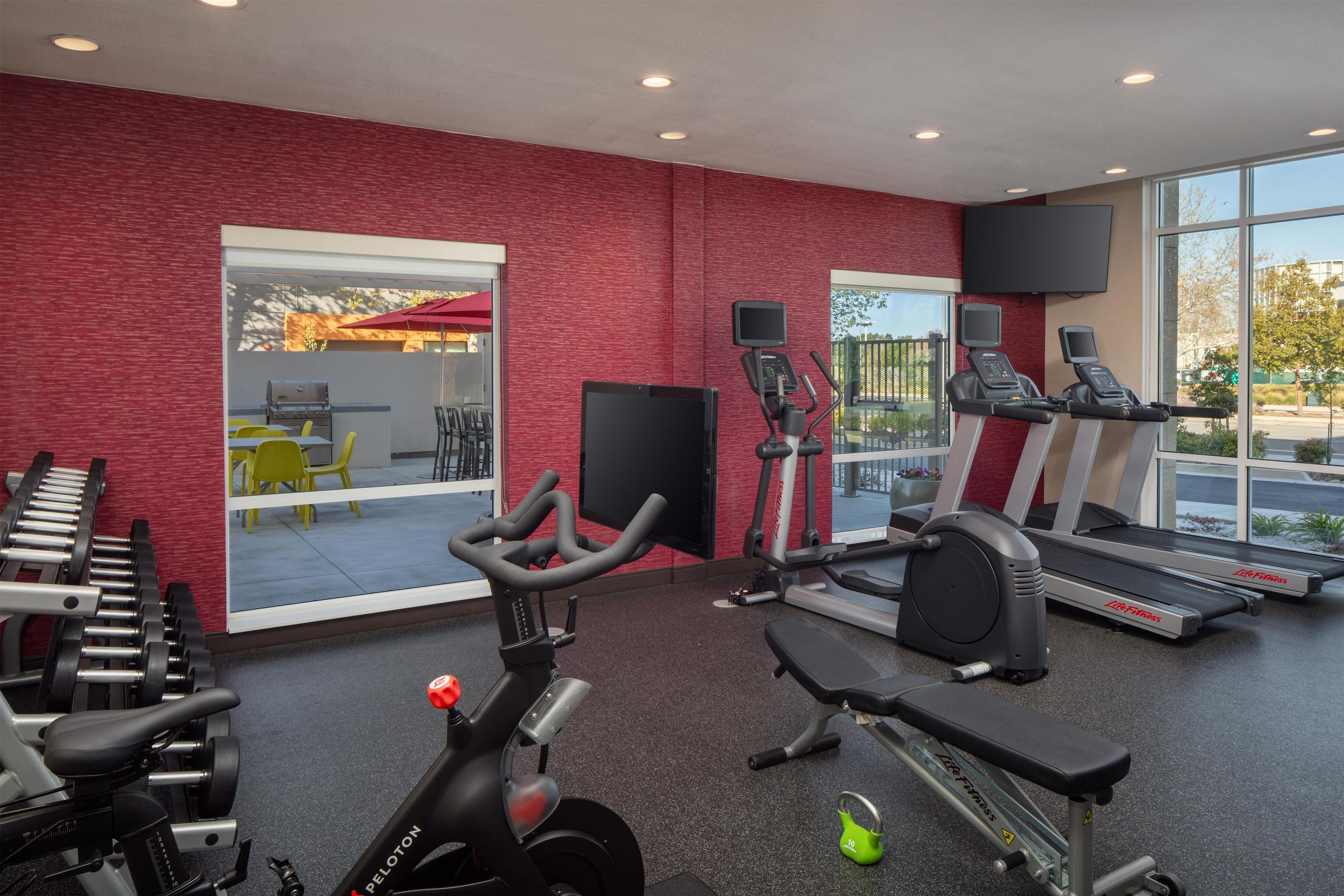 Un gimnasio con equipamiento de ejercicio, una cinta de correr y una bicicleta estática.