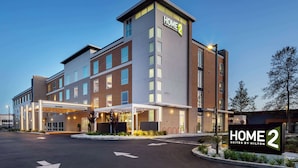 Een modern hotelgebouw met een bord waarop staat 'HOME 2 Suites by Hilton'.