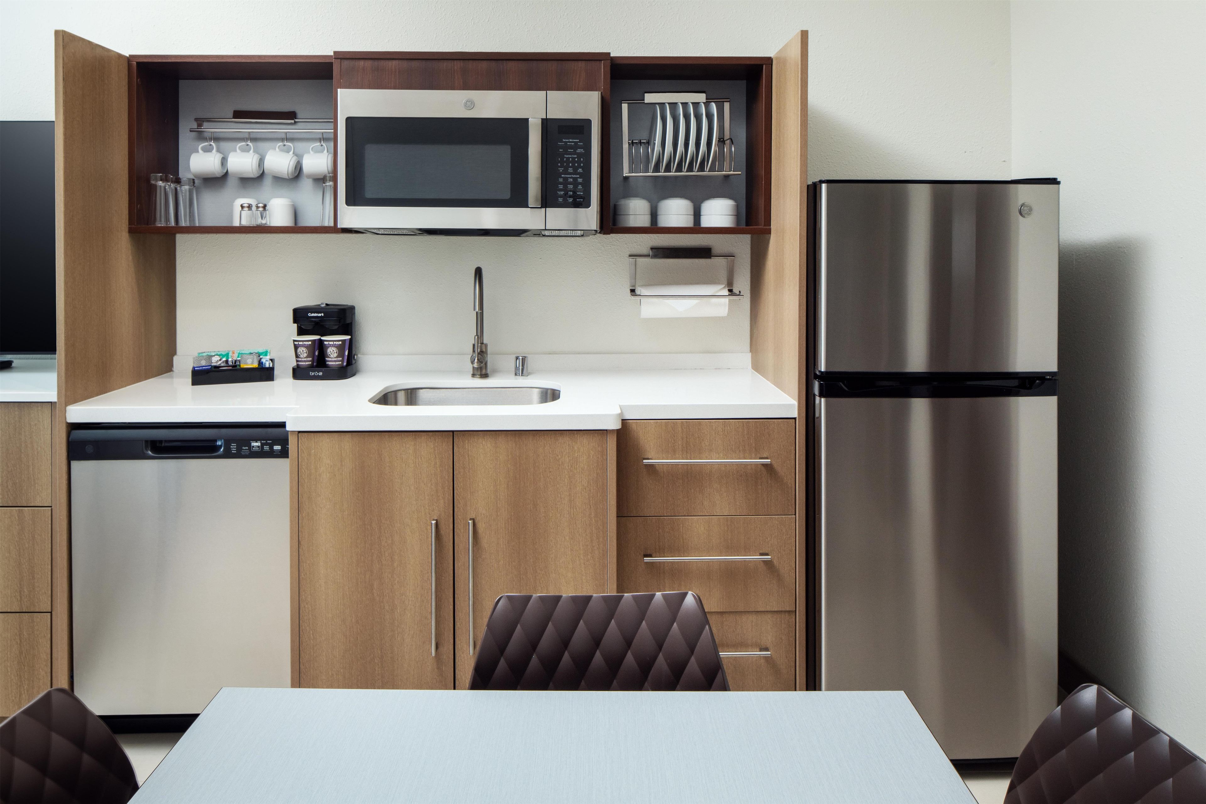 Cocina compacta equipada con microondas, refrigerador, cafetera y lavavajillas.