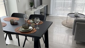 Et moderne spiseområde med et mørkt bord, stole og et fjernsyn på et hvidt skab.