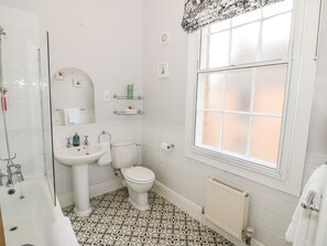 Un baño con bañera, lavabo, inodoro y ventana.