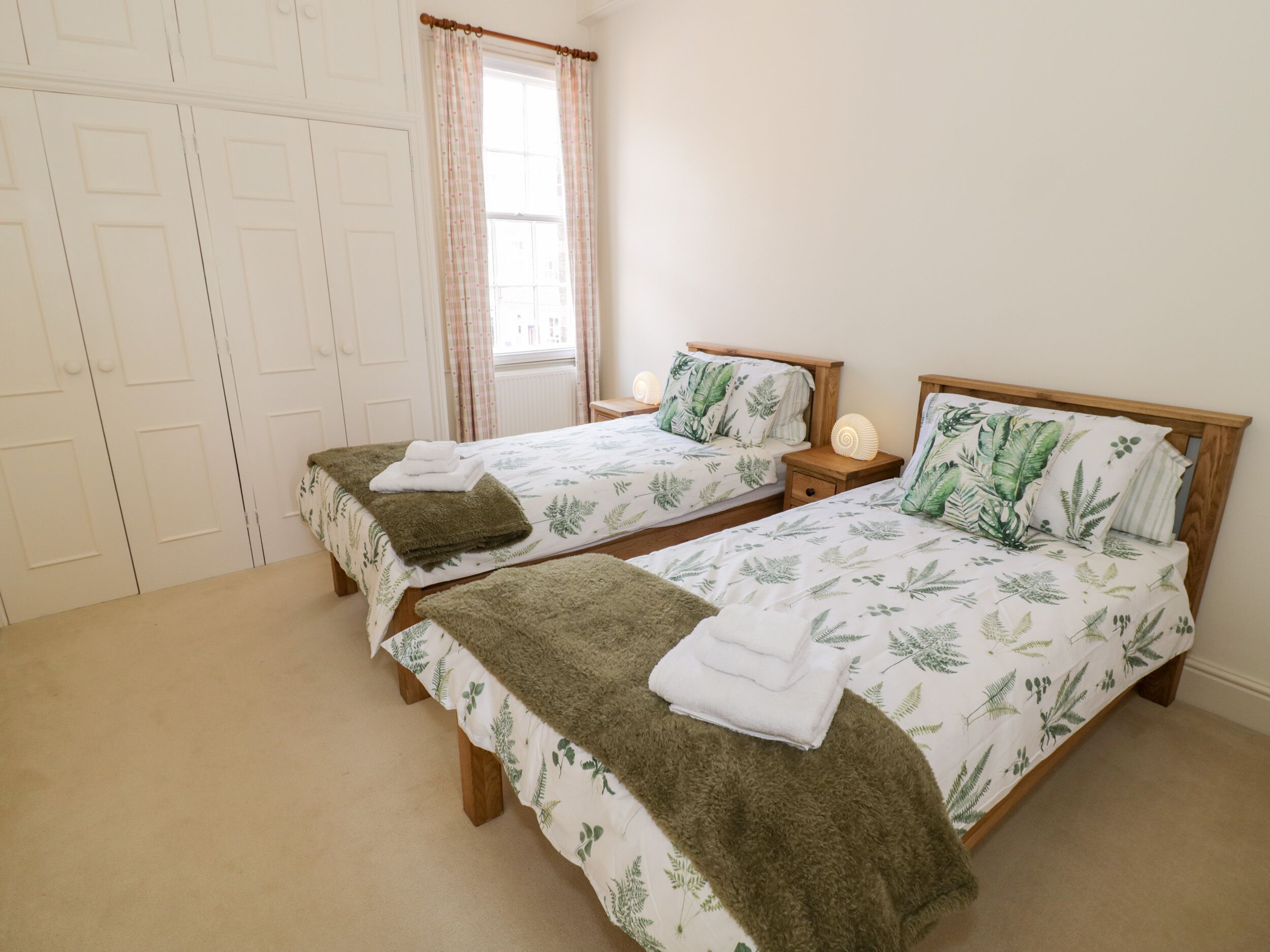 Un dormitorio con dos camas individuales, cada una con cabecero de madera y una mesita de noche.