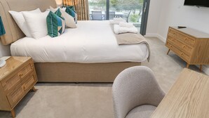 Un dormitorio con una cama grande, un aparador de madera, una silla, un televisor y vistas al exterior.