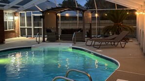 A pool area with a covered patio, lounge chairs, and a grill. - "Bayou Breeze" Private Pool (Heated) Gorgeous Home! Bikes, Game room (Navarre)