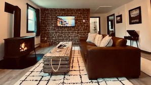 A cozy living room with a stone wall, a fireplace, a comfortable sofa, and a coffee table.