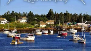 A harbor with multiple boats docked, surrounded by houses and greenery.