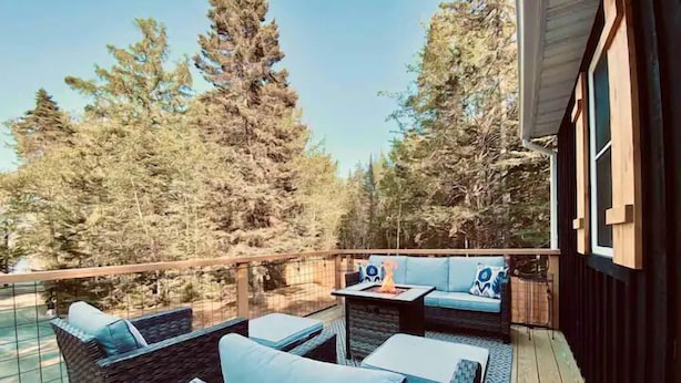 An outdoor deck with wicker furniture and a fire pit.