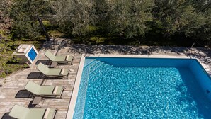 A rectangular swimming pool with clear blue water, surrounded by a wooden deck. - The Olive Poolhouse (Split)