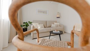 A living room with a sofa, a coffee table, a potted plant, and a framed picture on the wall. - The Olive Poolhouse (Split)