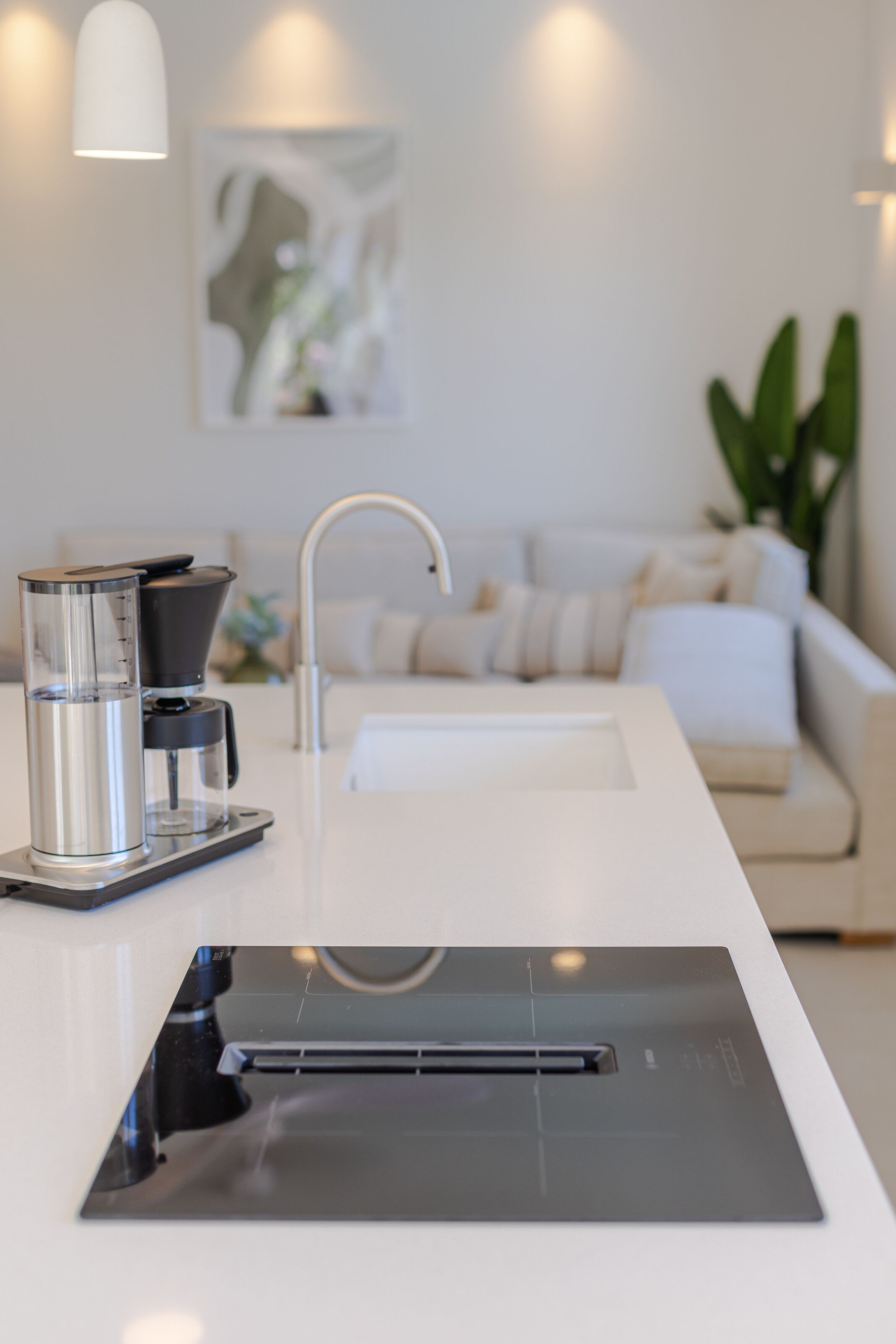 A modern kitchen with a coffee maker, a sink, and a countertop.