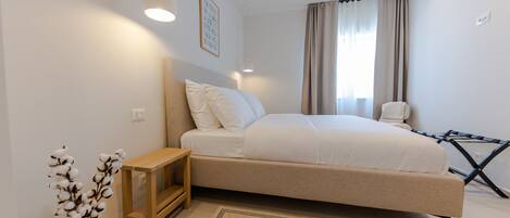 A bedroom with a bed, bedside table, lamp, and a vase with flowers.