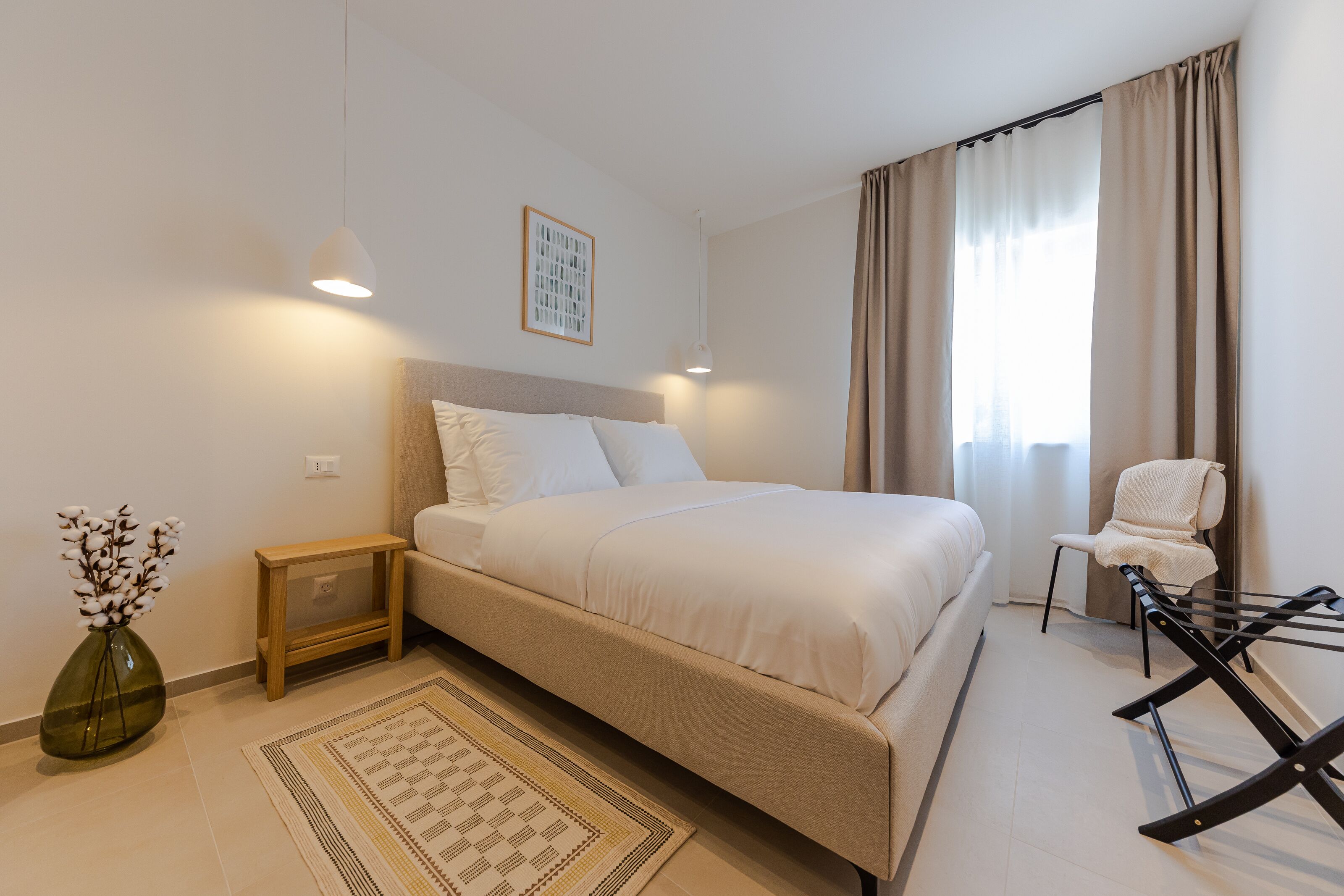 A modern bedroom with a large bed, bedside tables, a chair, and a small table.