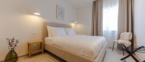 A modern bedroom with a large bed, bedside tables, a chair, and a small table.
