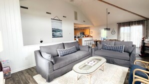 Un salon spacieux avec un canapé gris, une table basse et un tapis à motifs.
