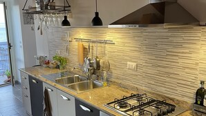 A modern kitchen with a gas stove, stainless steel sink, and wooden accents.