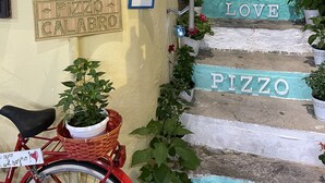 A red bicycle parked outside a building with a sign reading "VICOBENE" and a welcome sign.