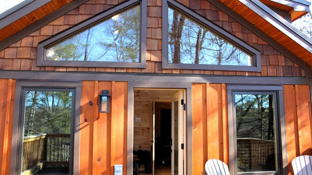Eine Hütte mit zwei großen Fenstern und einer Terrasse.