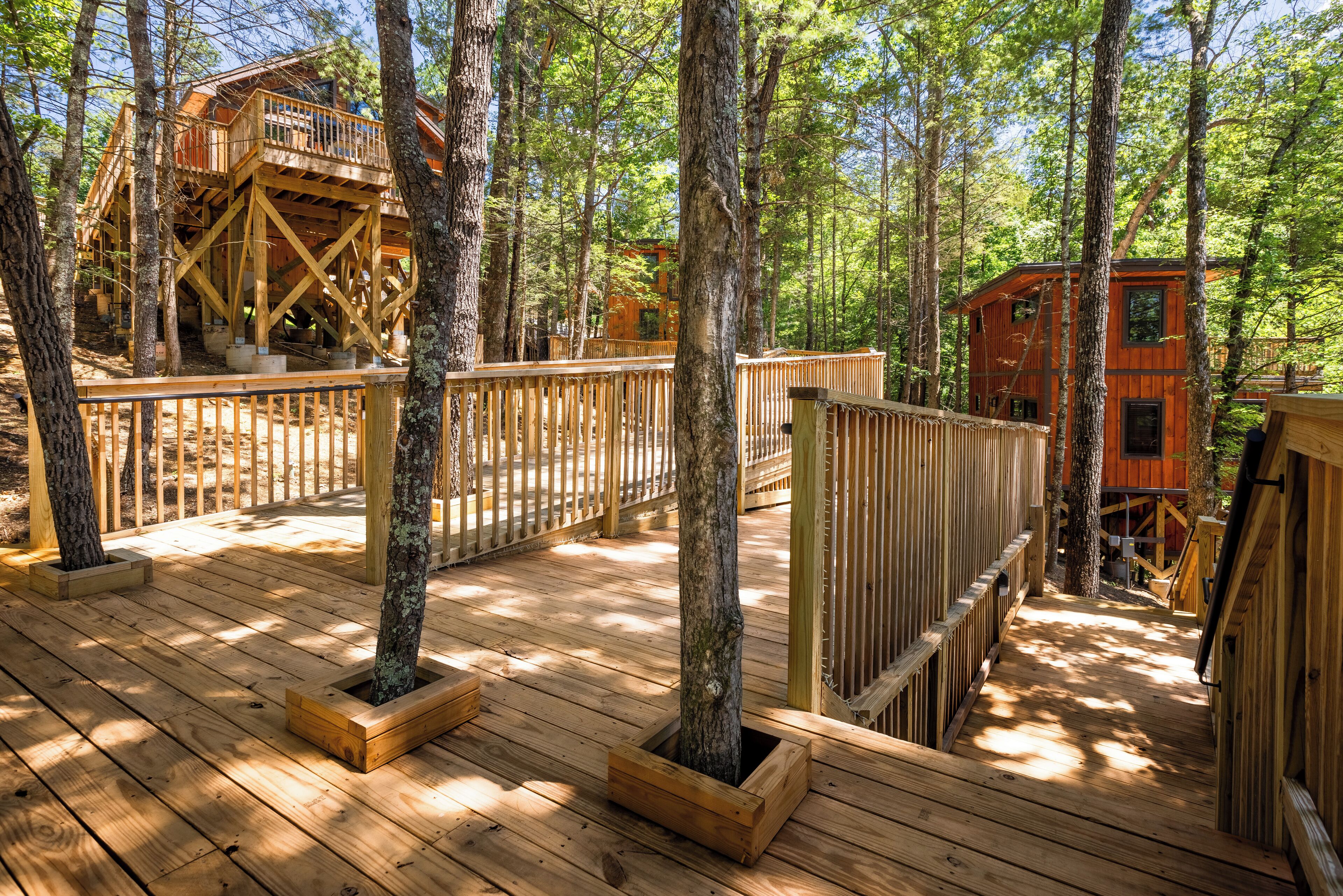 A wooden deck with built-in planters, a wooden fence, and a treehouse structure.