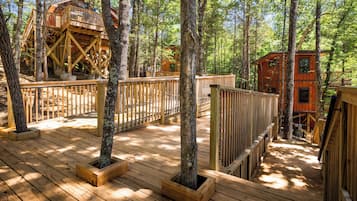 A wooden deck with built-in planters, a wooden fence, and a treehouse structure.