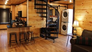 Une cuisine compacte dotée d’un îlot central, d’un lave-linge encastré et d’un escalier en colimaçon.
