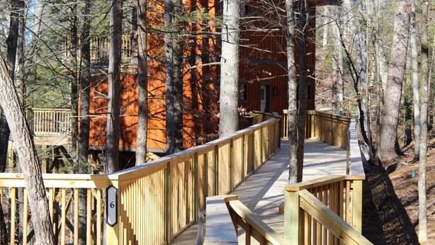 Une terrasse en bois menant à un chalet entouré d’arbres.