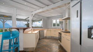 Een moderne keuken met een rond eiland, een inbouwvaatwasser en een grote koelkast.