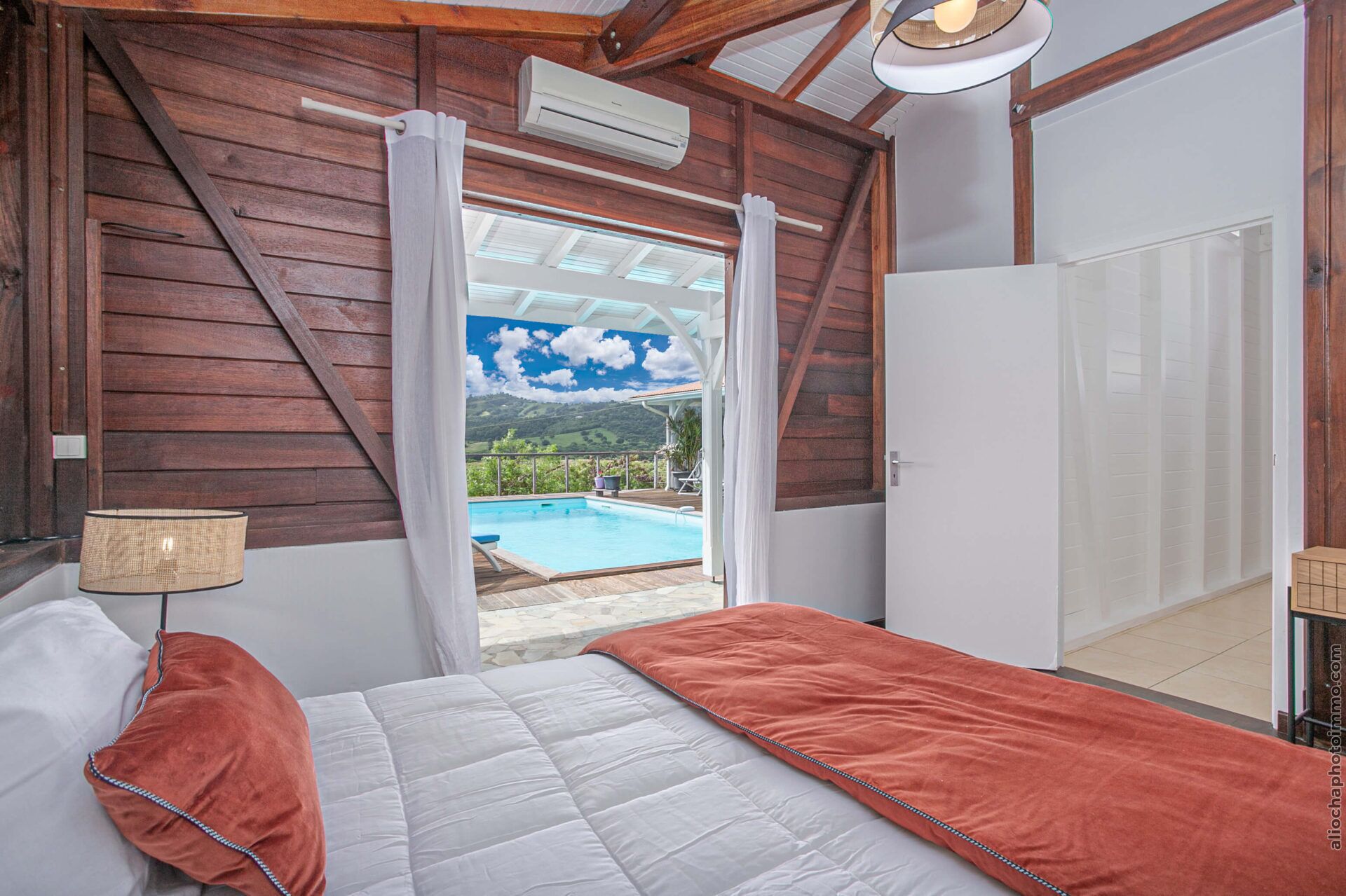 A bedroom with a view of a swimming pool and hills.
