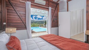 Een slaapkamer met uitzicht op een zwembad en heuvels.
